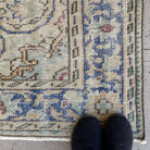 Close-up of the blue vintage Turkish area rug showing medallion details, hand-knotted weave, wool and cotton and low pile.