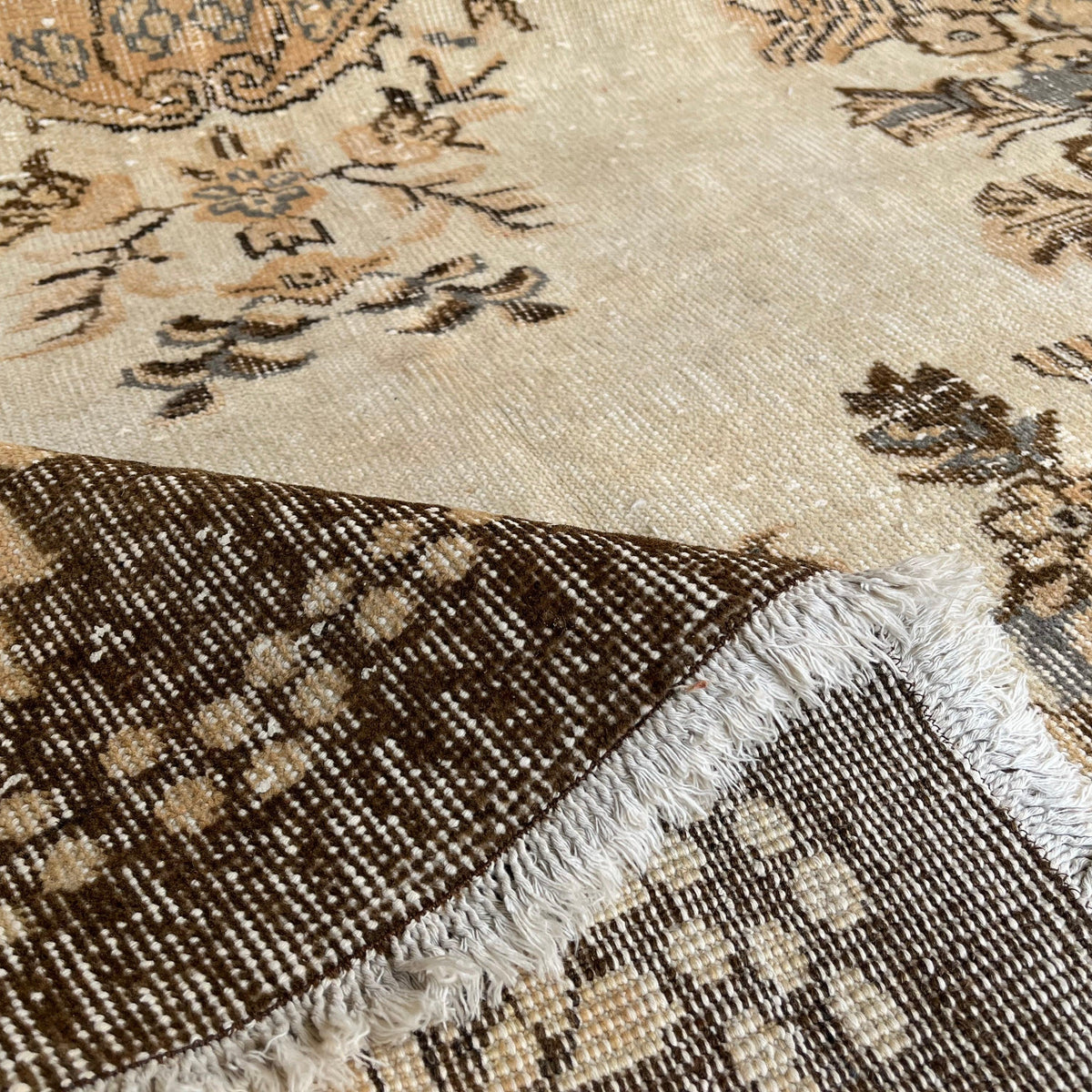 Close-up of the brown vintage Turkish area rug showing medallion details, hand-knotted weave, wool and cotton and low pile.