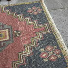 Close-up of the red vintage Turkish distressed rug showing traditional details, hand-knotted weave, wool and cotton and low pile.