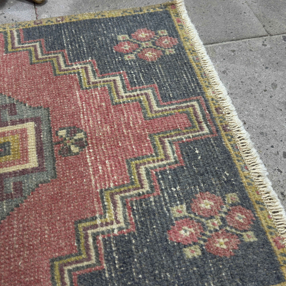 Close-up of the red vintage Turkish distressed rug showing traditional details, hand-knotted weave, wool and cotton and low pile.