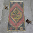 Red 1' x 3' vintage Turkish distressed rug in wool and cotton, shown on the floor.