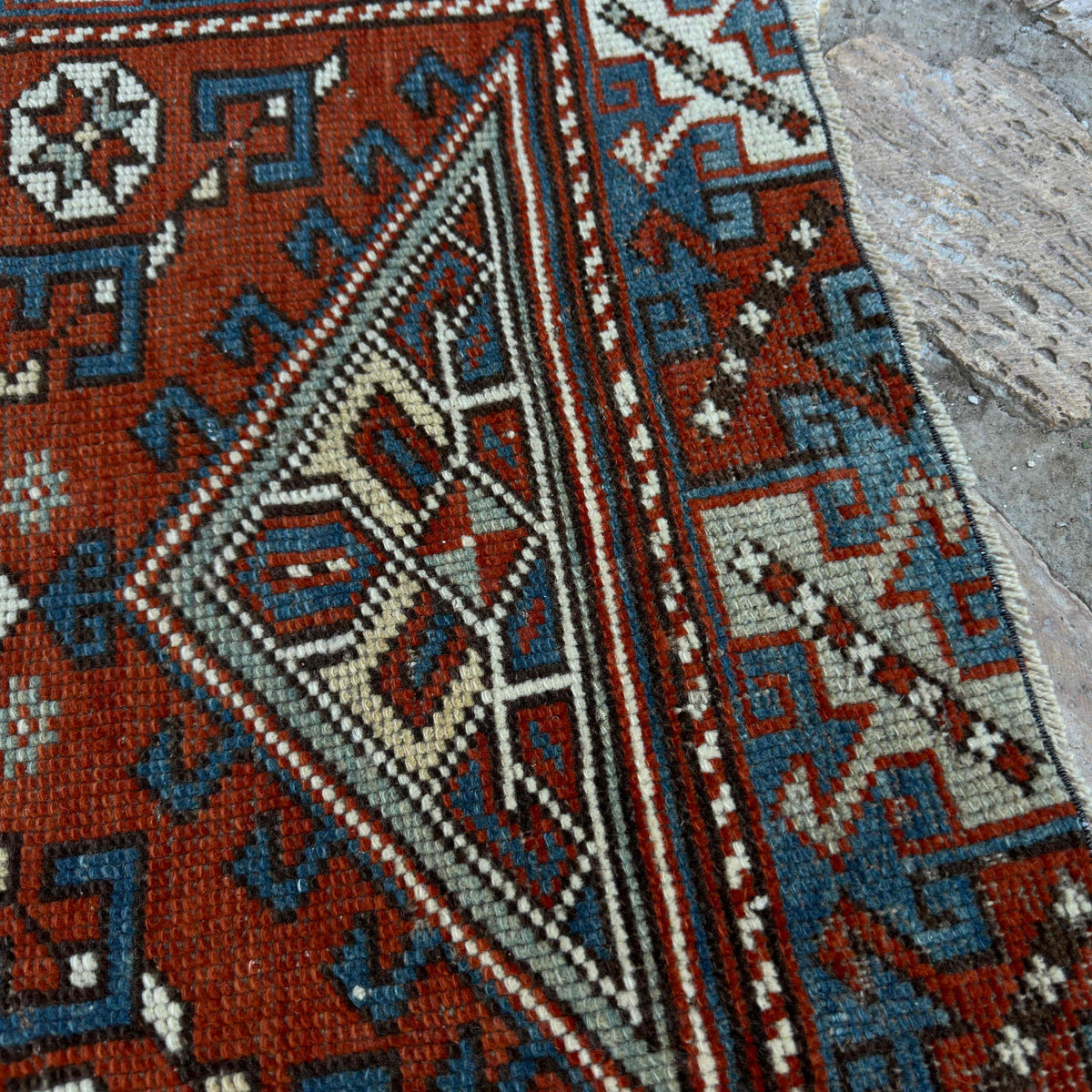 Close-up of the red vintage Turkish distressed rug showing traditional details, hand-knotted weave, wool and cotton and low pile.