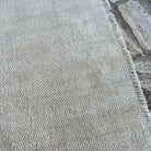 Close-up of the beige vintage Turkish distressed rug showing neutral details, hand-knotted weave, wool and cotton and low pile.