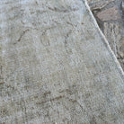 Close-up of the beige vintage Turkish distressed rug showing neutral details, hand-knotted weave, wool and cotton and low pile.