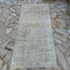 Beige 3' x 6' vintage Turkish distressed rug in wool and cotton, shown on the floor.