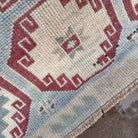 Close-up of the blue vintage Turkish distressed rug showing traditional details, hand-knotted weave, wool and cotton and low pile.