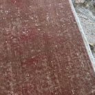 Close-up of the pale red vintage Turkish distressed rug showing patchwork details, hand-knotted weave, wool and cotton and low pile.