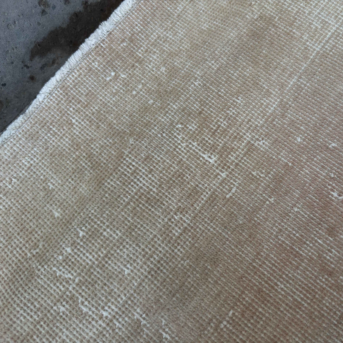 Close-up of the beige vintage Turkish distressed rug showing neutral details, hand-knotted weave, wool and cotton and low pile.