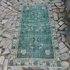 Green 4' x 6' vintage Turkish distressed rug in wool and cotton, shown on the floor.