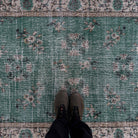 1970s green vintage Turkish distressed rug with traditional design, hand-knotted weave and low pile.