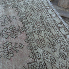 Close-up of the pale pink vintage Turkish distressed rug showing neutral details, hand-knotted weave, wool and cotton and low pile.