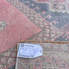 Close-up of the pink vintage Turkish distressed rug showing geometric details, hand-knotted weave, wool and cotton and low pile.