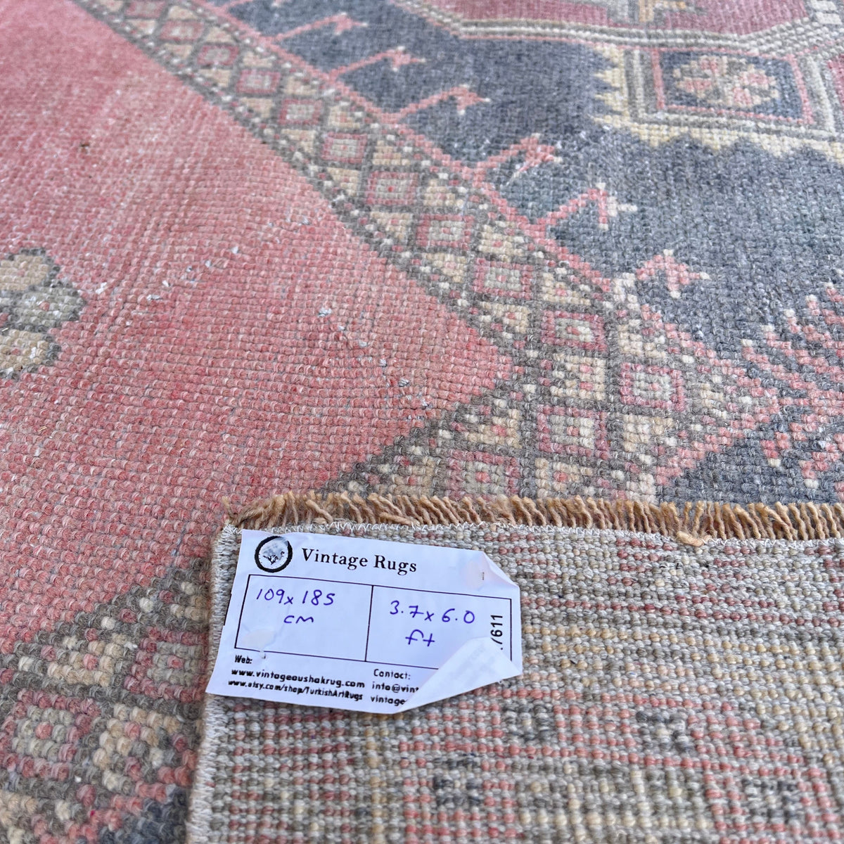 Close-up of the pink vintage Turkish distressed rug showing geometric details, hand-knotted weave, wool and cotton and low pile.