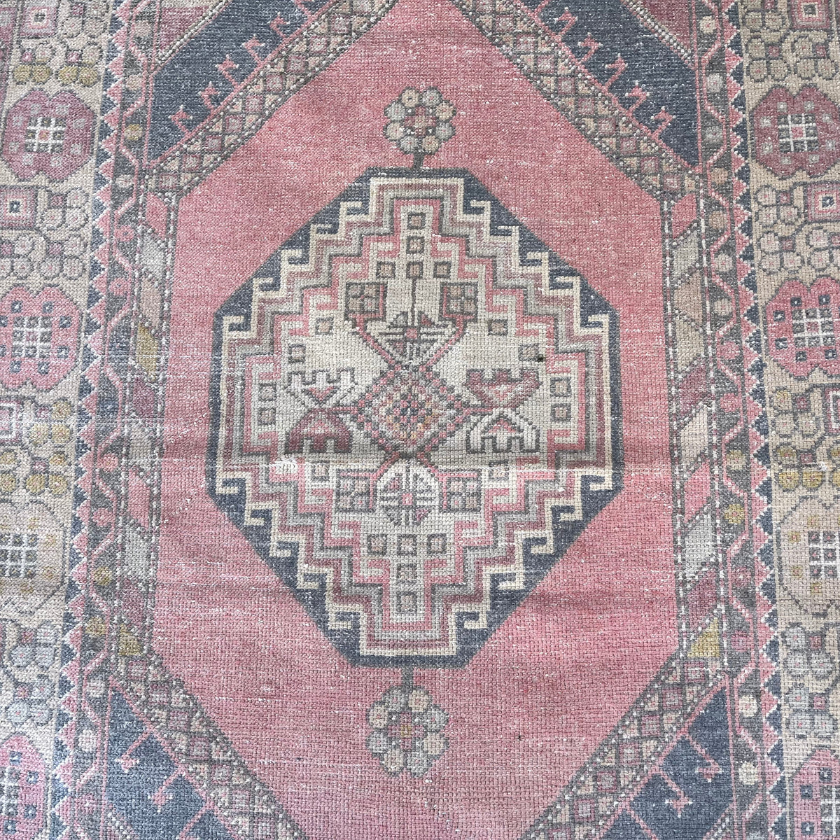 1970s pink vintage Turkish distressed rug with geometric design, hand-knotted weave and low pile.