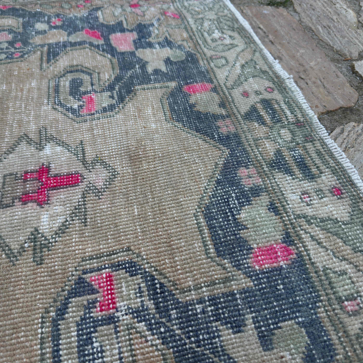 Close-up of the beige vintage Turkish distressed rug showing traditional details, hand-knotted weave, wool and cotton and low pile.