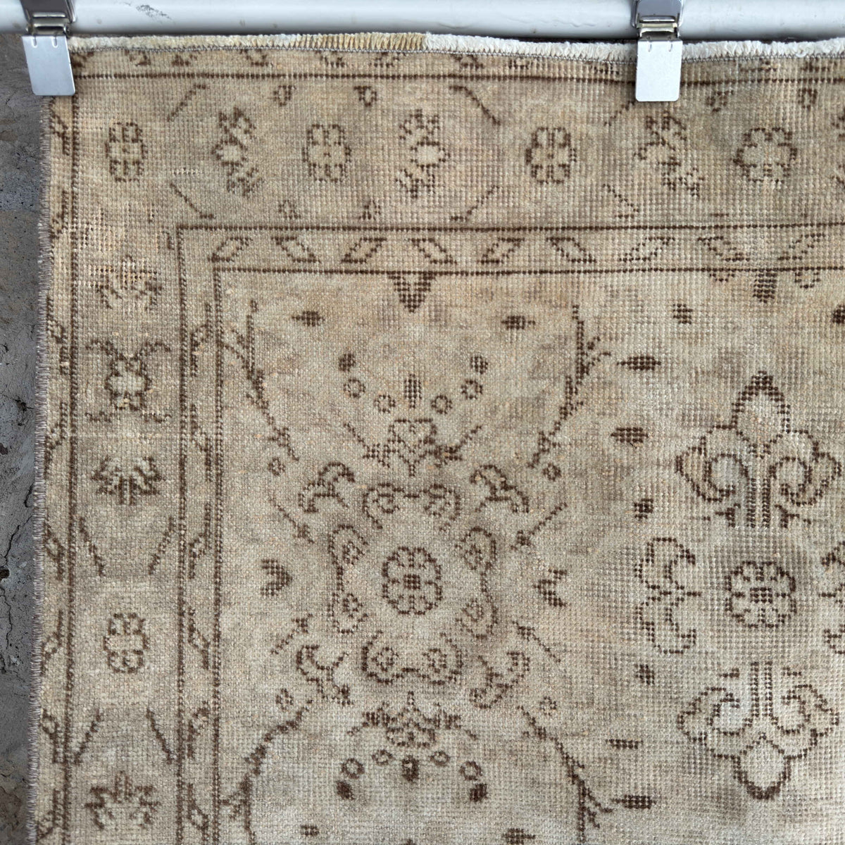 Close-up of the beige vintage Turkish distressed rug showing floral details, hand-knotted weave, wool and cotton and low pile.