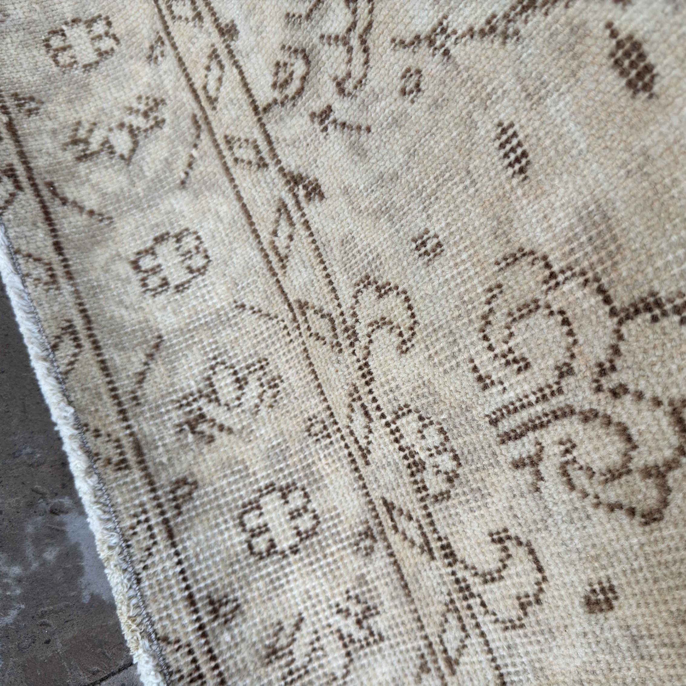 1970s beige vintage Turkish distressed rug with floral design, hand-knotted weave and low pile.