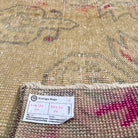 Close-up of the beige vintage Turkish distressed rug showing neutral details, hand-knotted weave, wool and cotton and low pile.