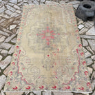 Beige 4' x 7' vintage Turkish distressed rug in wool and cotton, shown on the floor.