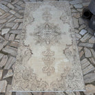 Beige 4' x 7' vintage Turkish distressed rug in wool and cotton, shown on the floor.