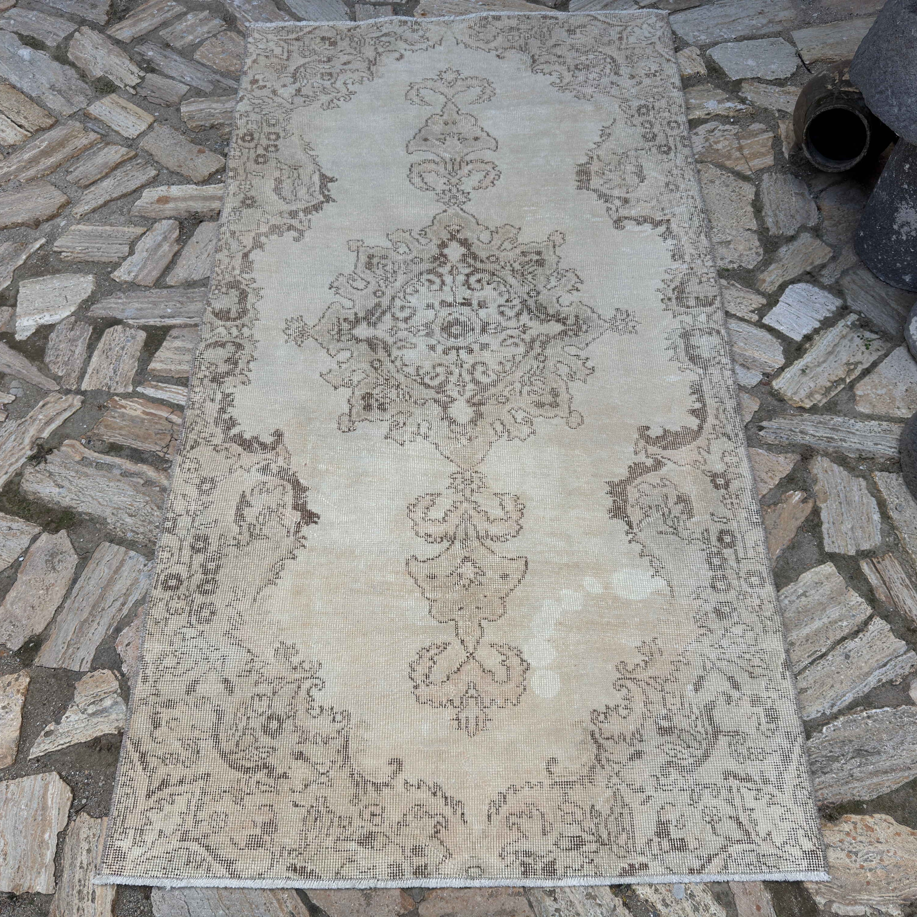 Beige 4' x 7' vintage Turkish distressed rug in wool and cotton, shown on the floor.