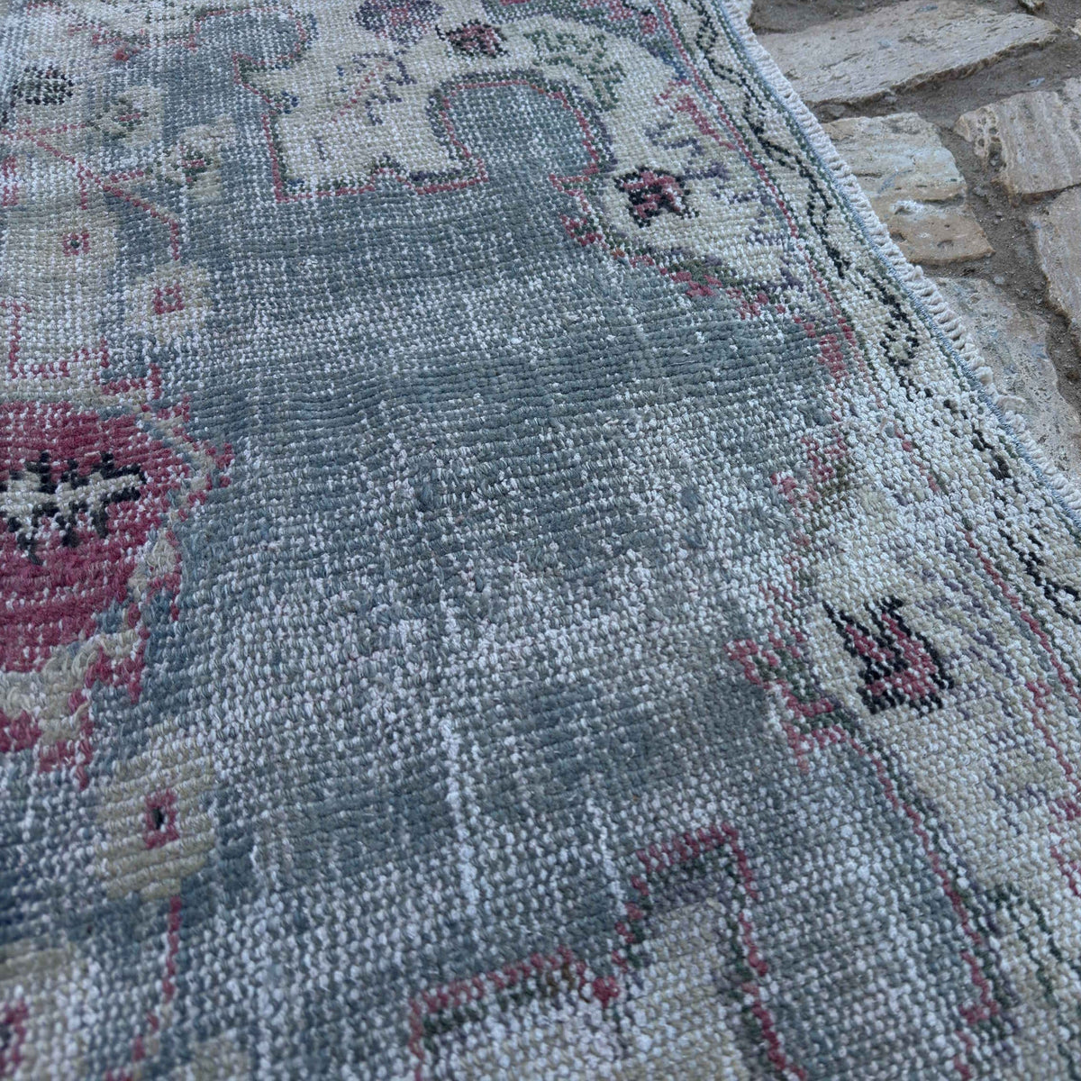 Close-up of the blue vintage Turkish distressed rug showing medallion details, hand-knotted weave, wool and cotton and low pile.
