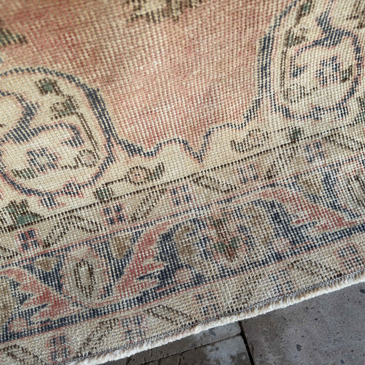 Close-up of the pink vintage Turkish distressed rug showing traditional details, hand-knotted weave, wool and cotton and low pile.