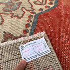 Close-up of the red vintage Turkish distressed rug showing geometric details, hand-knotted weave, wool and cotton and low pile.