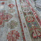 Close-up of the red vintage Turkish distressed rug showing traditional details, hand-knotted weave, wool and cotton and low pile.