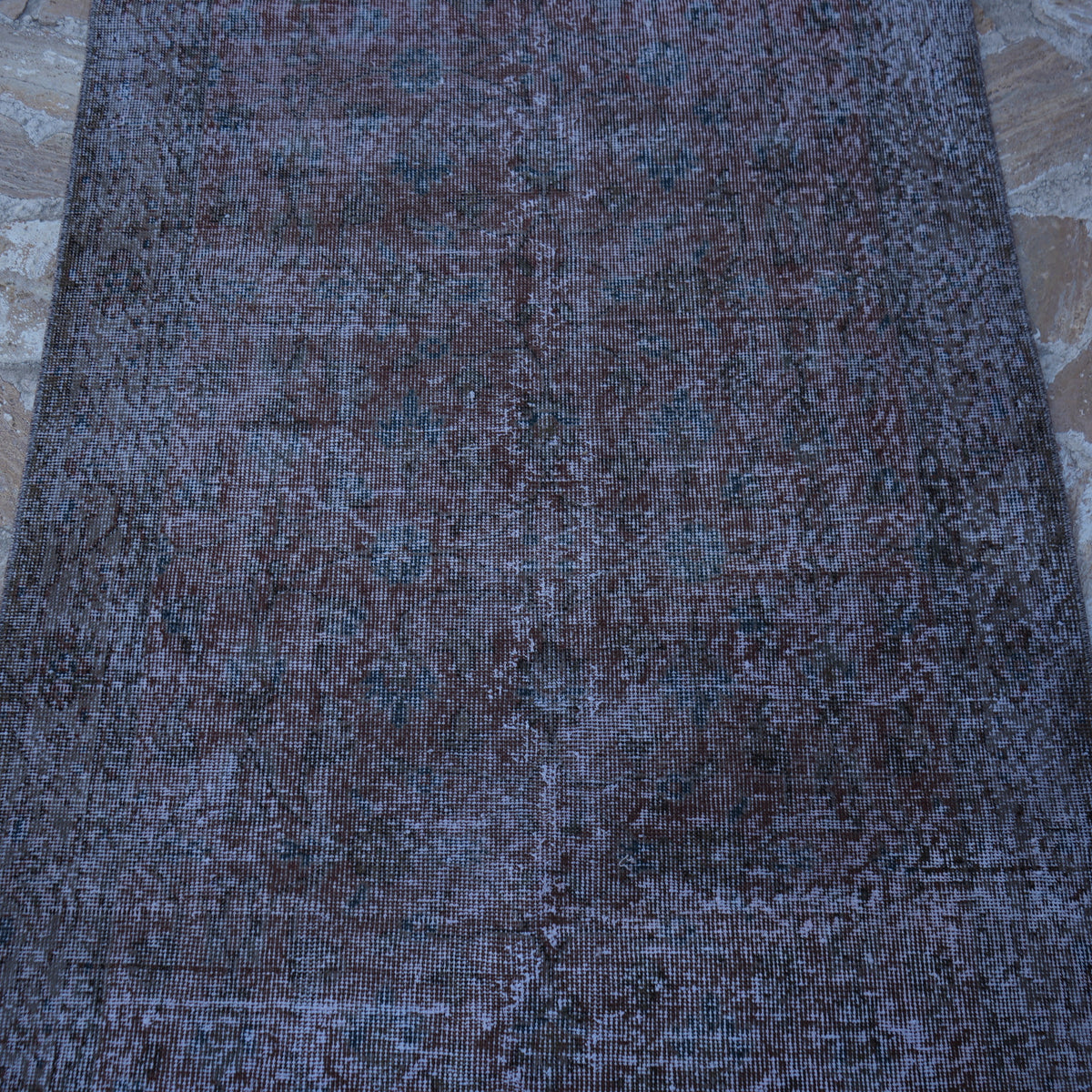 Close-up of the red vintage distressed rug showing floral details, hand-knotted weave, wool and cotton and low pile.