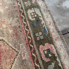 Close-up of the red vintage Turkish distressed rug showing traditional details, hand-knotted weave, wool and cotton and low pile.