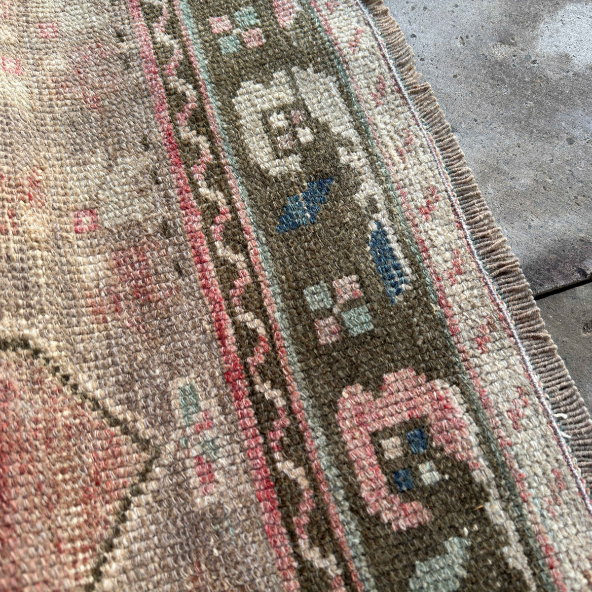 Close-up of the red vintage Turkish distressed rug showing traditional details, hand-knotted weave, wool and cotton and low pile.