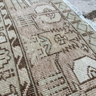 Close-up of the beige vintage Turkish distressed rug showing neutral details, hand-knotted weave, wool and cotton and low pile.