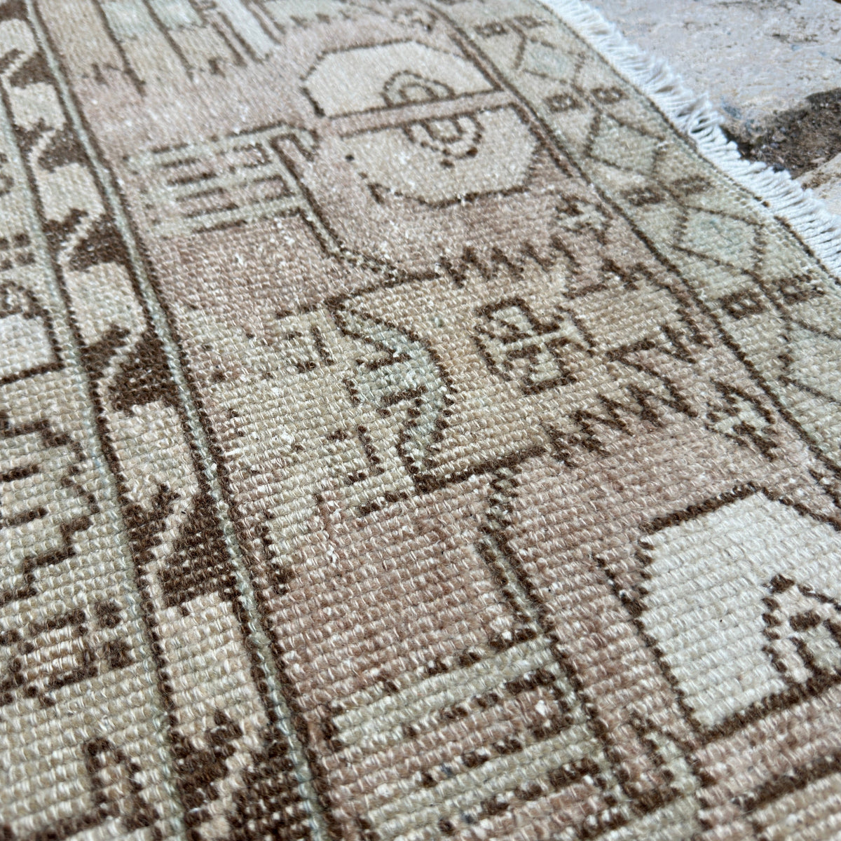 Close-up of the beige vintage Turkish distressed rug showing neutral details, hand-knotted weave, wool and cotton and low pile.