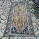 Pink 4' x 9' vintage Turkish distressed rug in wool and cotton, shown on the floor.
