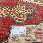 Close-up of the red vintage Turkish distressed rug showing traditional details, hand-knotted weave, wool and cotton and low pile.