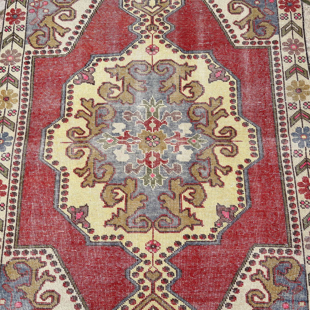1970s red vintage Turkish distressed rug with traditional design, hand-knotted weave and low pile.