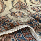Close-up of the beige vintage Turkish distressed rug showing traditional details, hand-knotted weave, wool and cotton and low pile.
