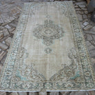 Beige 5' x 8' vintage Turkish distressed rug in wool and cotton, shown on the floor.