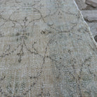 Close-up of the beige vintage Turkish distressed rug showing floral details, hand-knotted weave, wool and cotton and low pile.