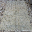 Beige 5' x 8' vintage Turkish distressed rug in wool and cotton, shown on the floor.