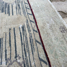 Close-up of the blue vintage Turkish distressed rug showing neutral details, hand-knotted weave, wool and cotton and low pile.