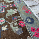 Close-up of the brown vintage Turkish distressed rug showing geometric details, hand-knotted weave, wool and cotton and low pile.