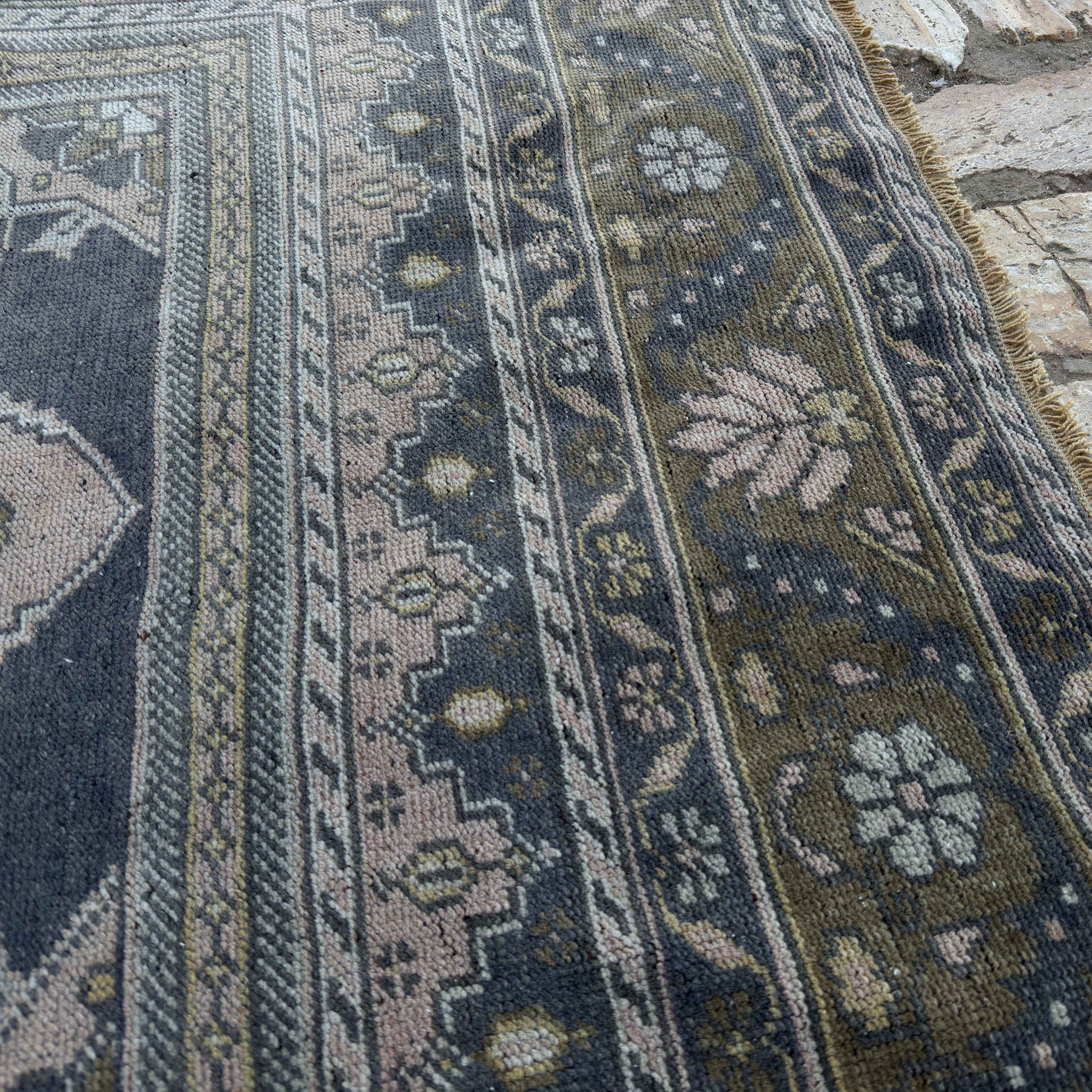 Close-up of the pink vintage Turkish distressed rug showing traditional details, hand-knotted weave, wool and cotton and low pile.
