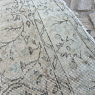 Close-up of the beige vintage Turkish distressed rug showing neutral details, hand-knotted weave, wool and cotton and low pile.