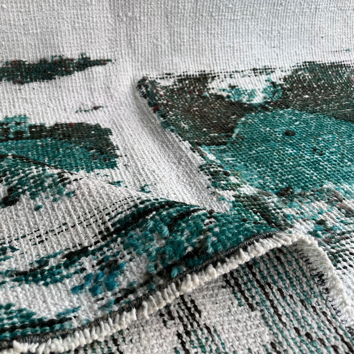 Close-up of the green vintage Turkish distressed rug showing overdyed details, hand-knotted weave, wool and cotton and low pile.