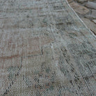 Close-up of the pale pink vintage Turkish distressed rug showing medallion details, hand-knotted weave, wool and cotton and low pile.
