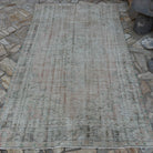 Pale Pink 5' x 9' vintage Turkish distressed rug in wool and cotton, shown on the floor.