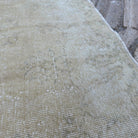 Close-up of the beige vintage Turkish distressed rug showing neutral details, hand-knotted weave, wool and cotton and low pile.