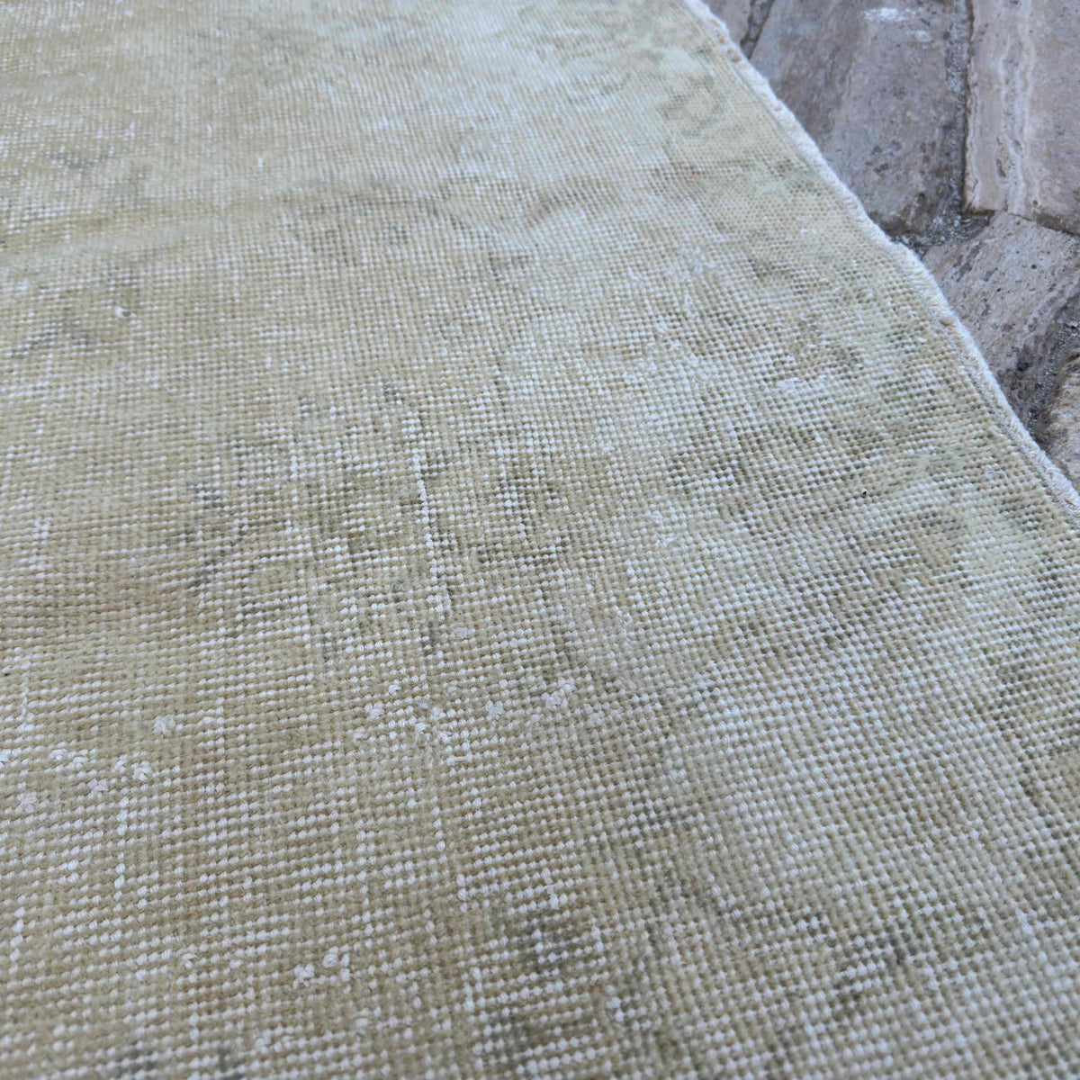 Close-up of the beige vintage Turkish distressed rug showing neutral details, hand-knotted weave, wool and cotton and low pile.